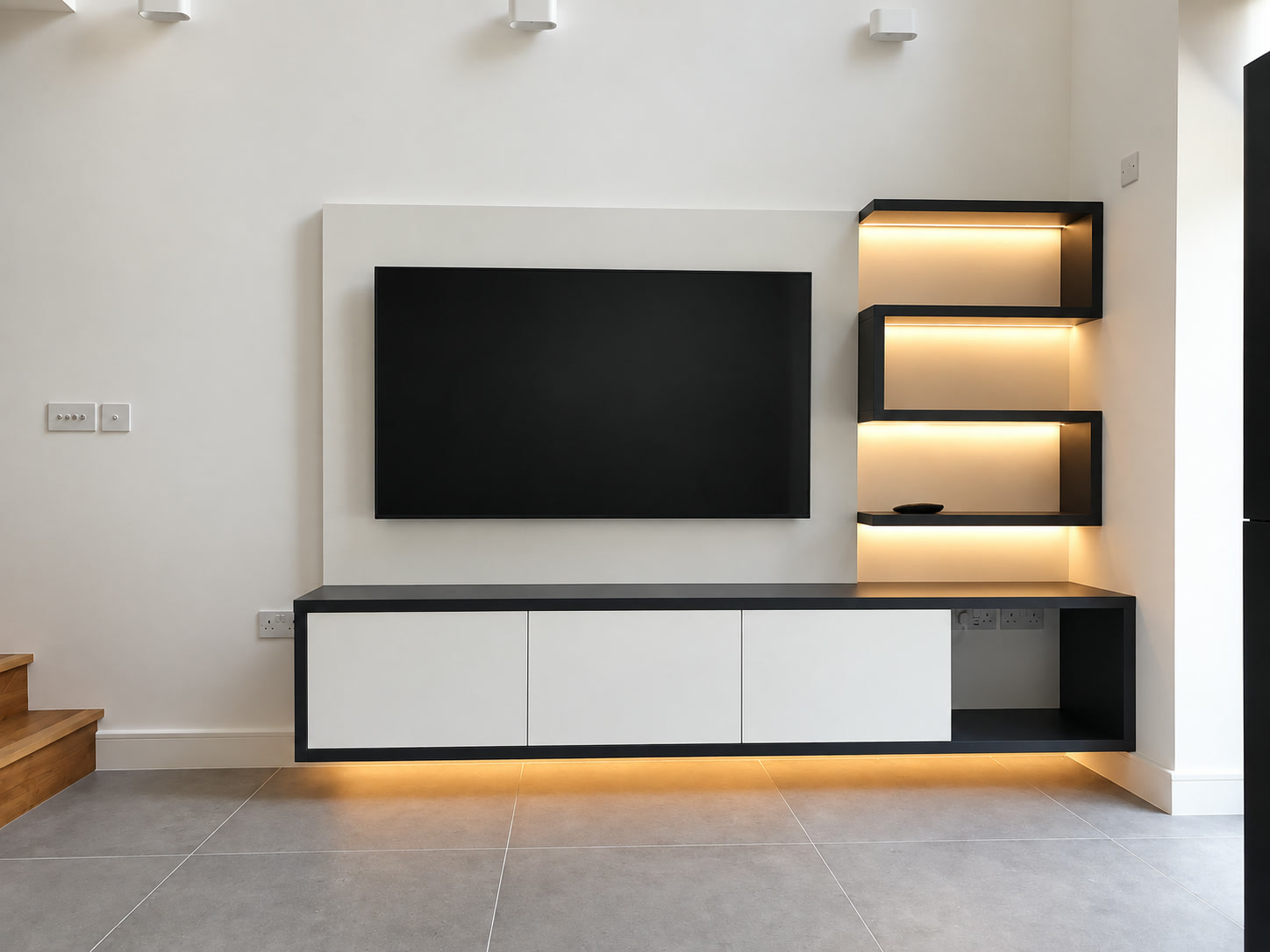Front view of a floating white fitted TV cabinet with three handleless doors and an open equipment shelf in London
