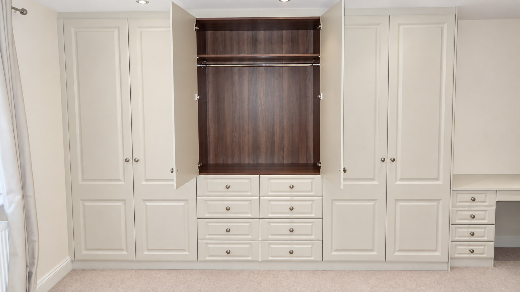 Open cream hinged fitted wardrobe with dark wood interior, hanging rail, top shelf and eight internal drawers