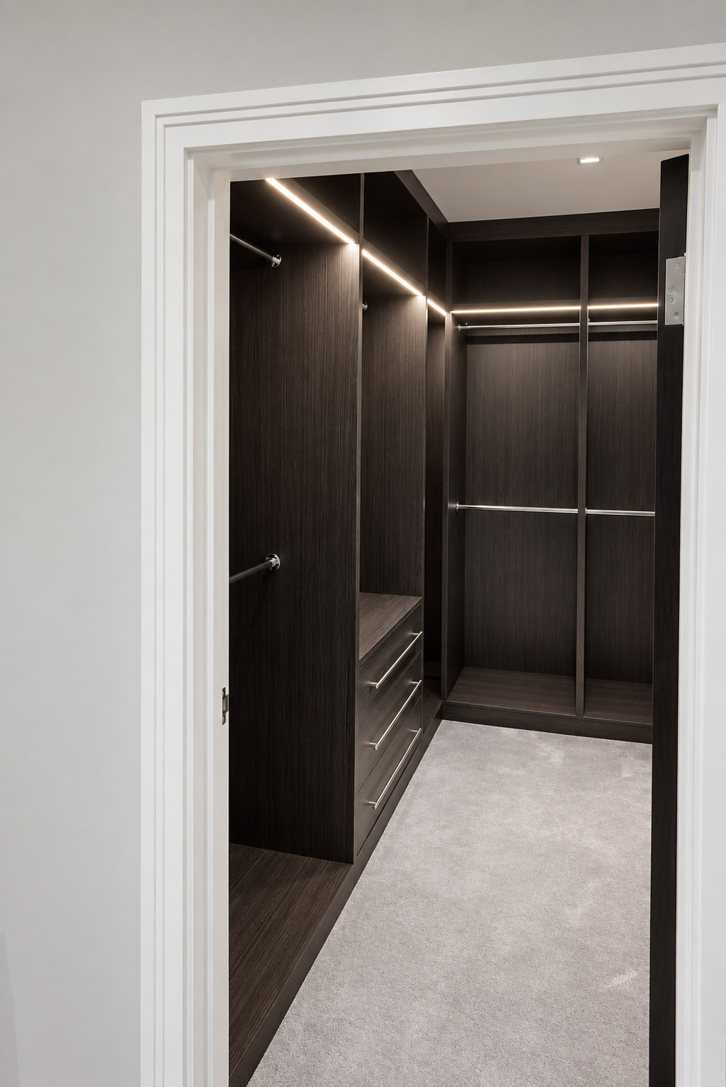 Dark LED-lit walk-in wardrobe viewed through the doorway