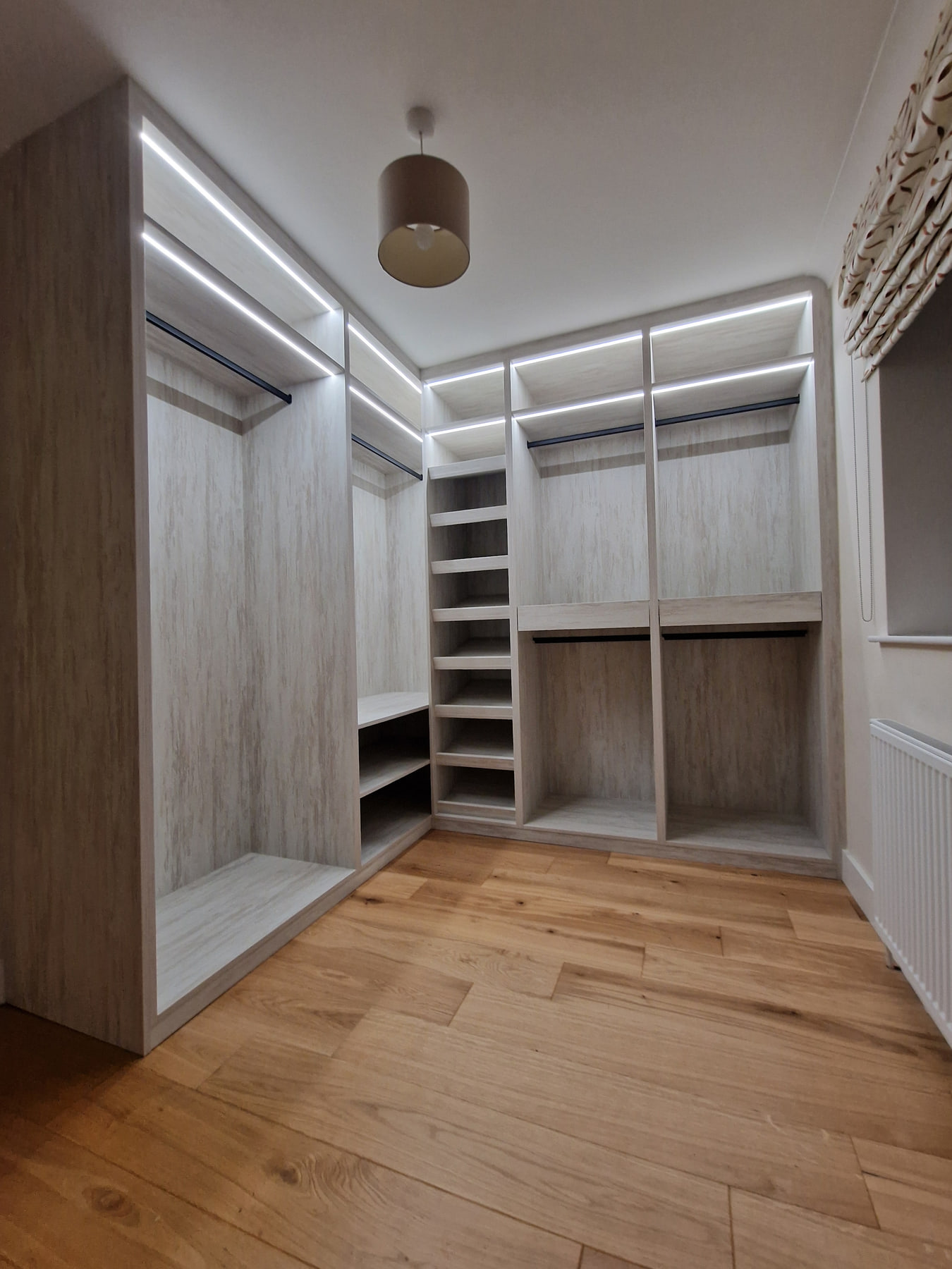 Wide view of an L-shaped walk-in wardrobe with open storage